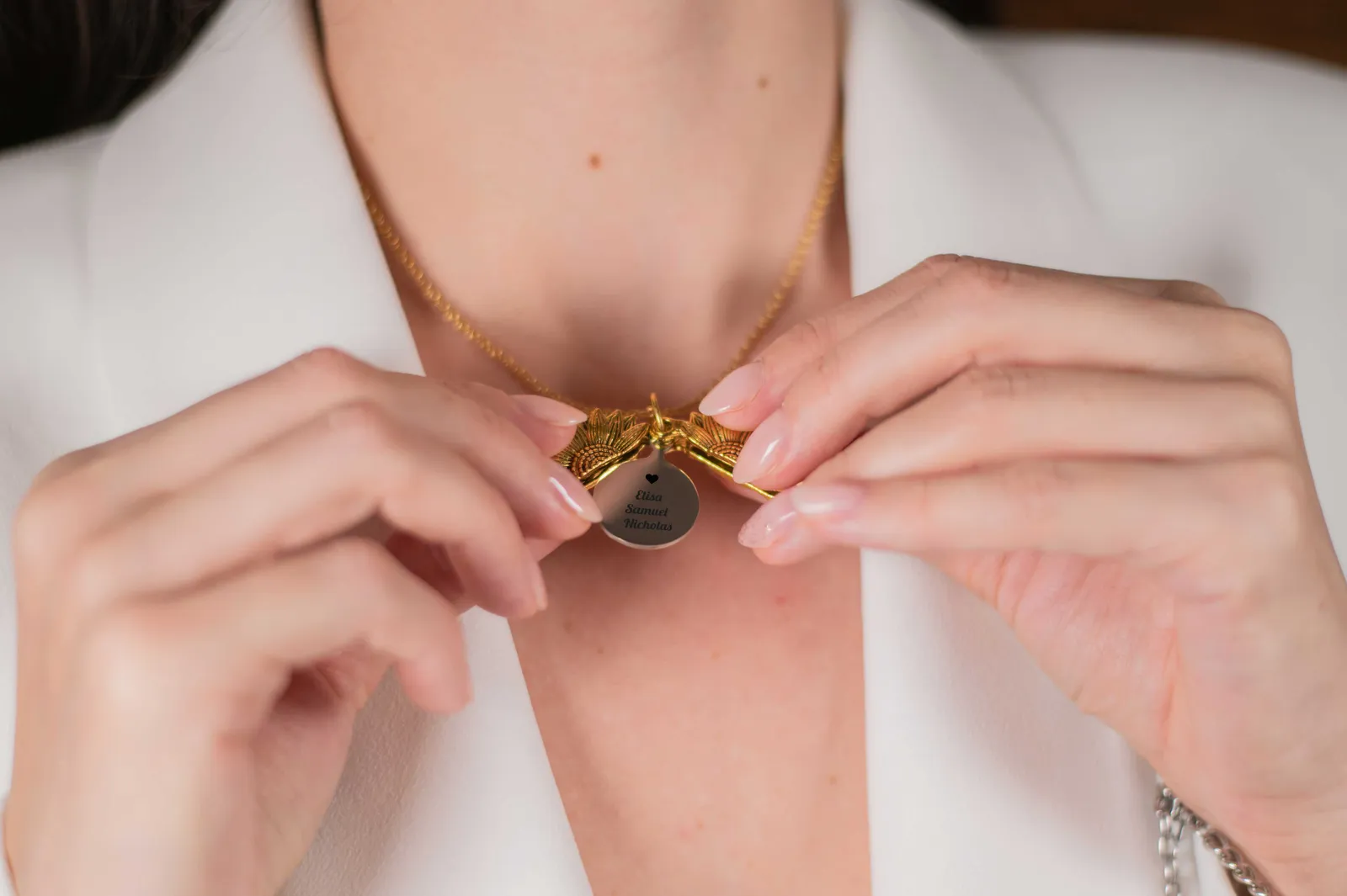 Collana a sole che si apre su un disco inciso con nomi, indossata