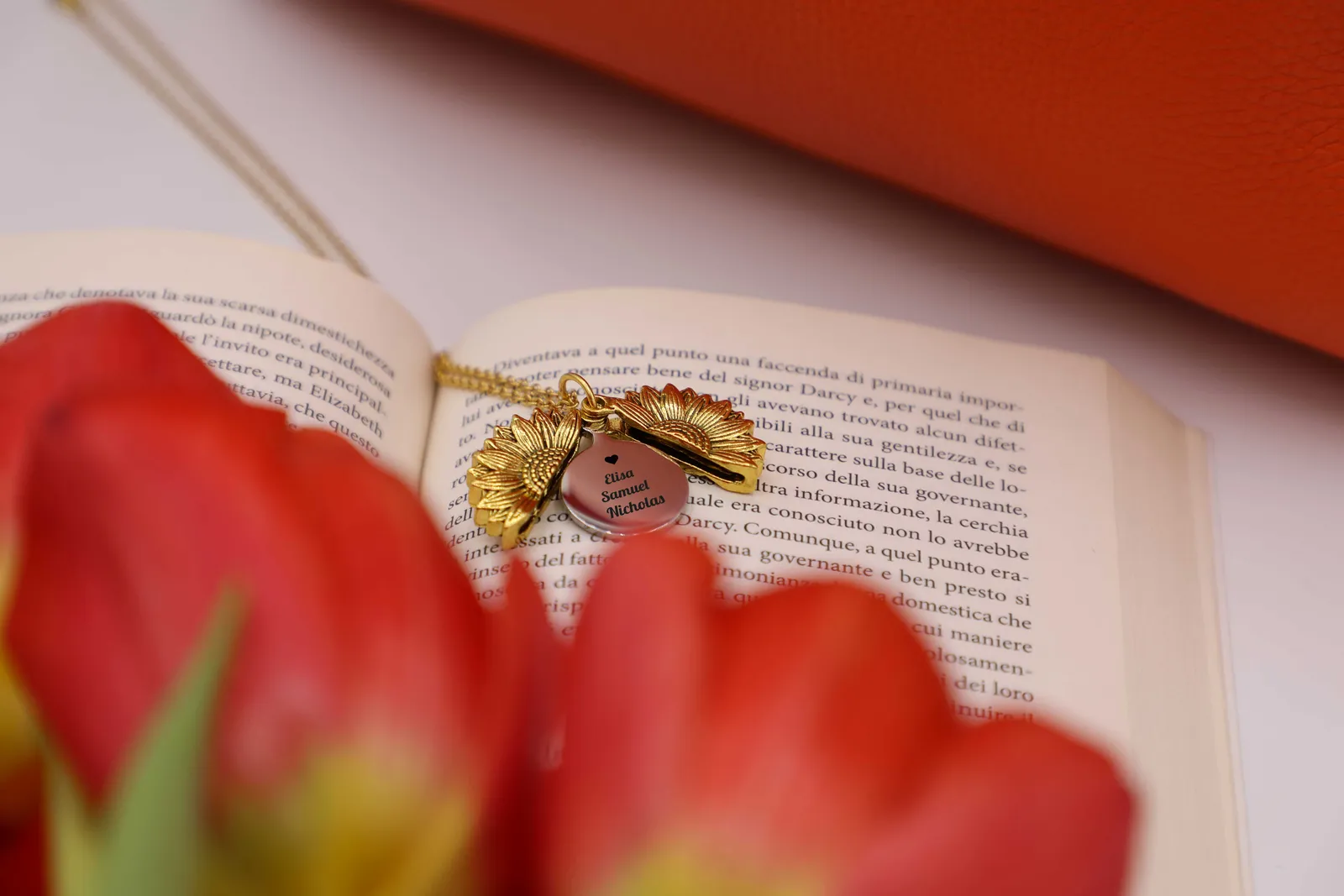 Collana Raggi di Memoria aperta su un libro, tra tulipani rossi