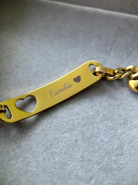 Bracciale dorato con la parola Familia e un cuore incisi in corsivo