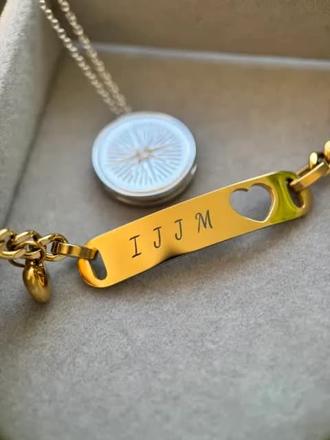 Bracciale dorato con le iniziali IJJM incise accanto a una medaglia in argento