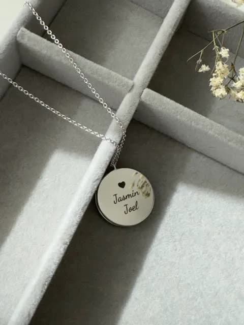 Medaglia tonda in argento con un cuore e i nomi Jasmin e Joel incisi in corsivo